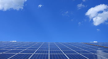 A low angle view of solar panels under a bright blue sky with clouds. HD wallpaper