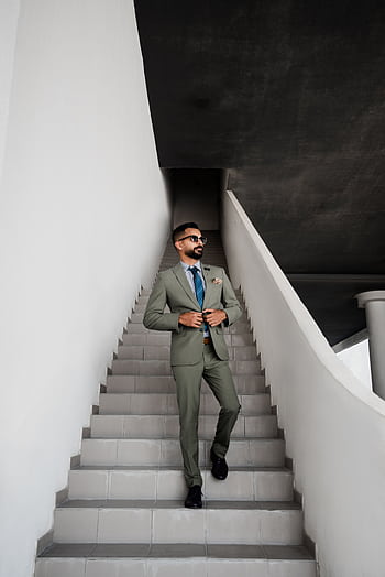A fashionable man in a suit walking up stairs in Dubai, projecting confidence and style. HD phone wallpaper