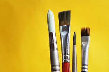 Close-up of varied paint brushes against a bright yellow backdrop. HD wallpaper