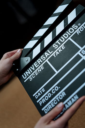 A detailed view of a Universal Studios clapboard held in hands, perfect for film industry concepts. HD phone wallpaper