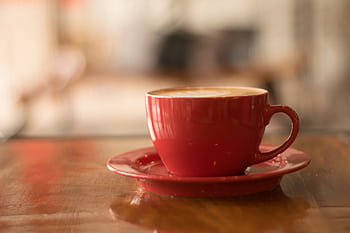 Cozy atmosphere with a cappuccino in a red cup on a wooden table, perfect for coffee lovers. HD wallpaper