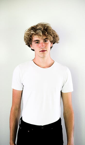 Portrait of a teenage boy with curly hair in a white shirt, standing against a white background. HD phone wallpaper