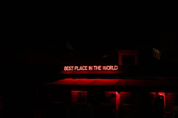 A captivating red neon sign illuminating a building facade at night, creating a vibrant and moody atmosphere. HD wallpaper