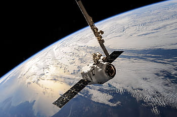 A satellite glides over Earth showcasing dramatic cloud formations and the vast expanse of space. HD wallpaper