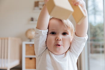 Adorable baby enjoying playtime with wooden blocks in a cozy indoor setting. Perfect depiction of joy and learning. HD wallpaper