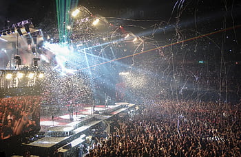 Vibrant concert scene with dynamic lighting, confetti, and a large enthusiastic crowd. HD wallpaper