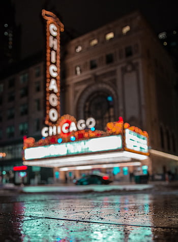Iconic Chicago Theater illuminated with neon lights reflecting on wet pavement at night. HD phone wallpaper