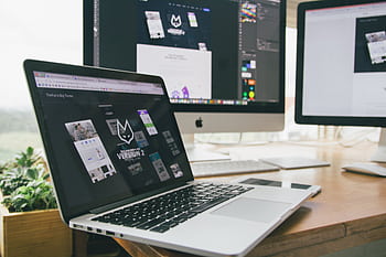 A stylish workspace featuring a laptop and monitors displaying design software. HD wallpaper