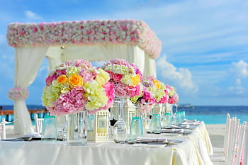 Beautiful seaside wedding setup with floral arrangements and pastel colors on a sunny day. HD wallpaper