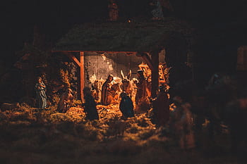 A detailed and festive nativity scene showcasing handcrafted figurines illuminated softly at night. HD wallpaper
