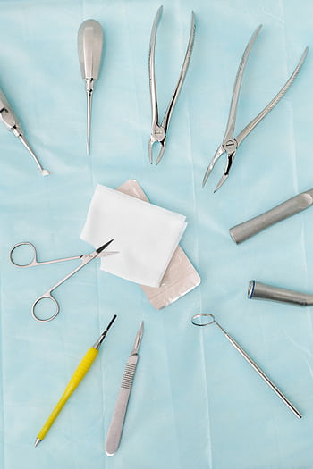Top view of assorted dental surgical instruments on a blue background, sterile and ready for use. HD phone wallpaper