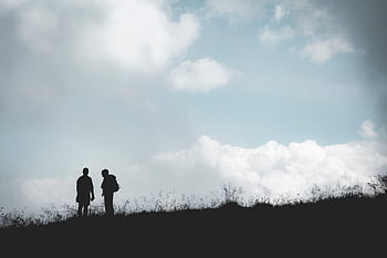 Silhouetted hikers on a hill with a cloudy sky background in Brienz, Switzerland. HD wallpaper