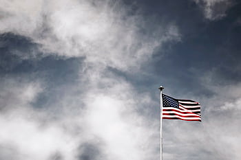 Vibrant American flag waving against a striking cloudy sky, symbolizing dom and patriotism. HD wallpaper