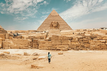 Tourist exploring the ancient Great Sphinx of Giza and Pyramid in Egypt's desert landscape. HD wallpaper